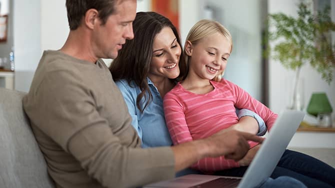 En privat blog kan forhindre fremmede i at kende de mere personlige detaljer om din familie. Billedet viser to forældre og deres datter i en sofa, hvor de kigger på en tablet sammen.